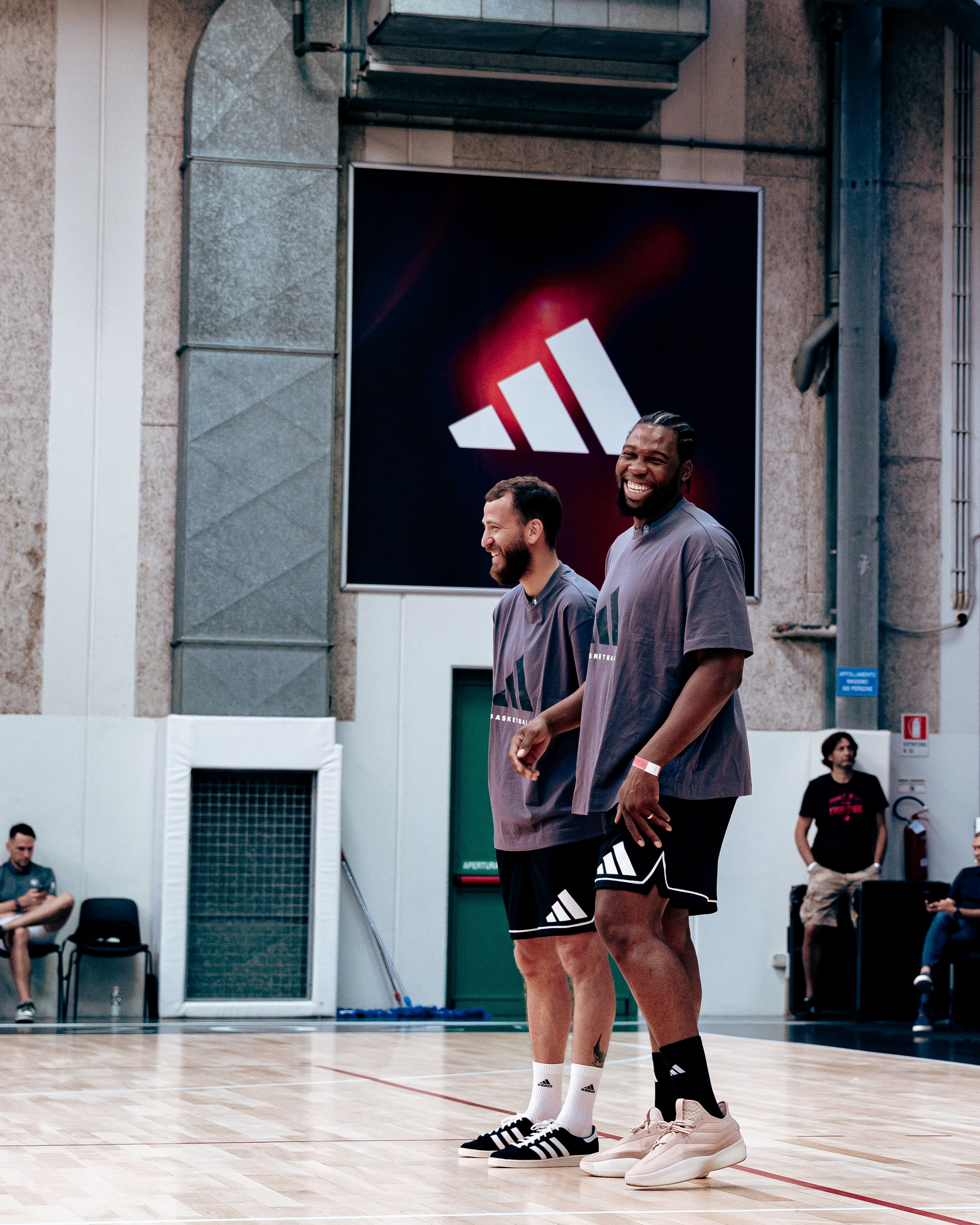 Two coaches laughing near adidas logo