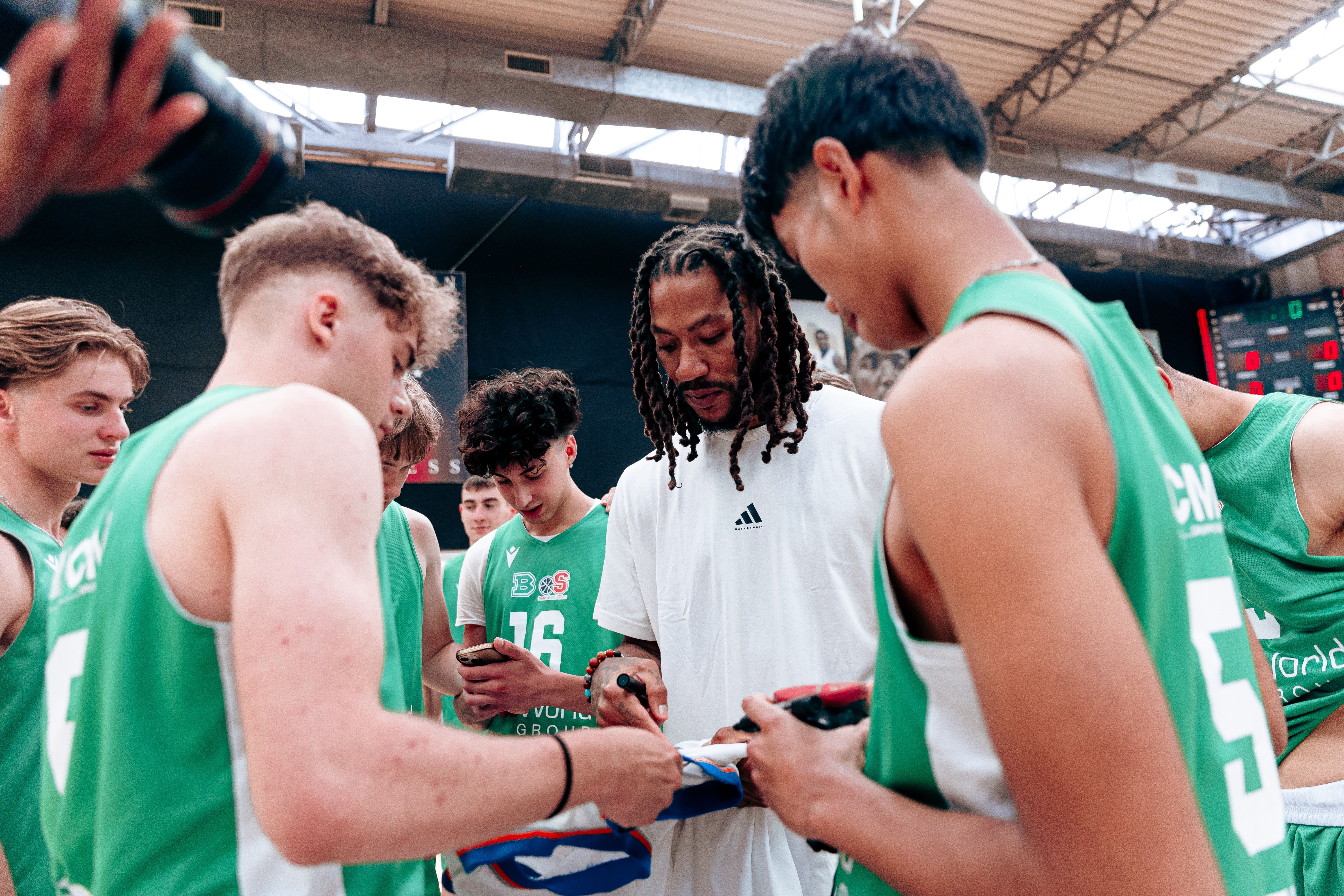 Young basketball players surrounding an NBA athlete for autographs at adidas Eurocamp 2025