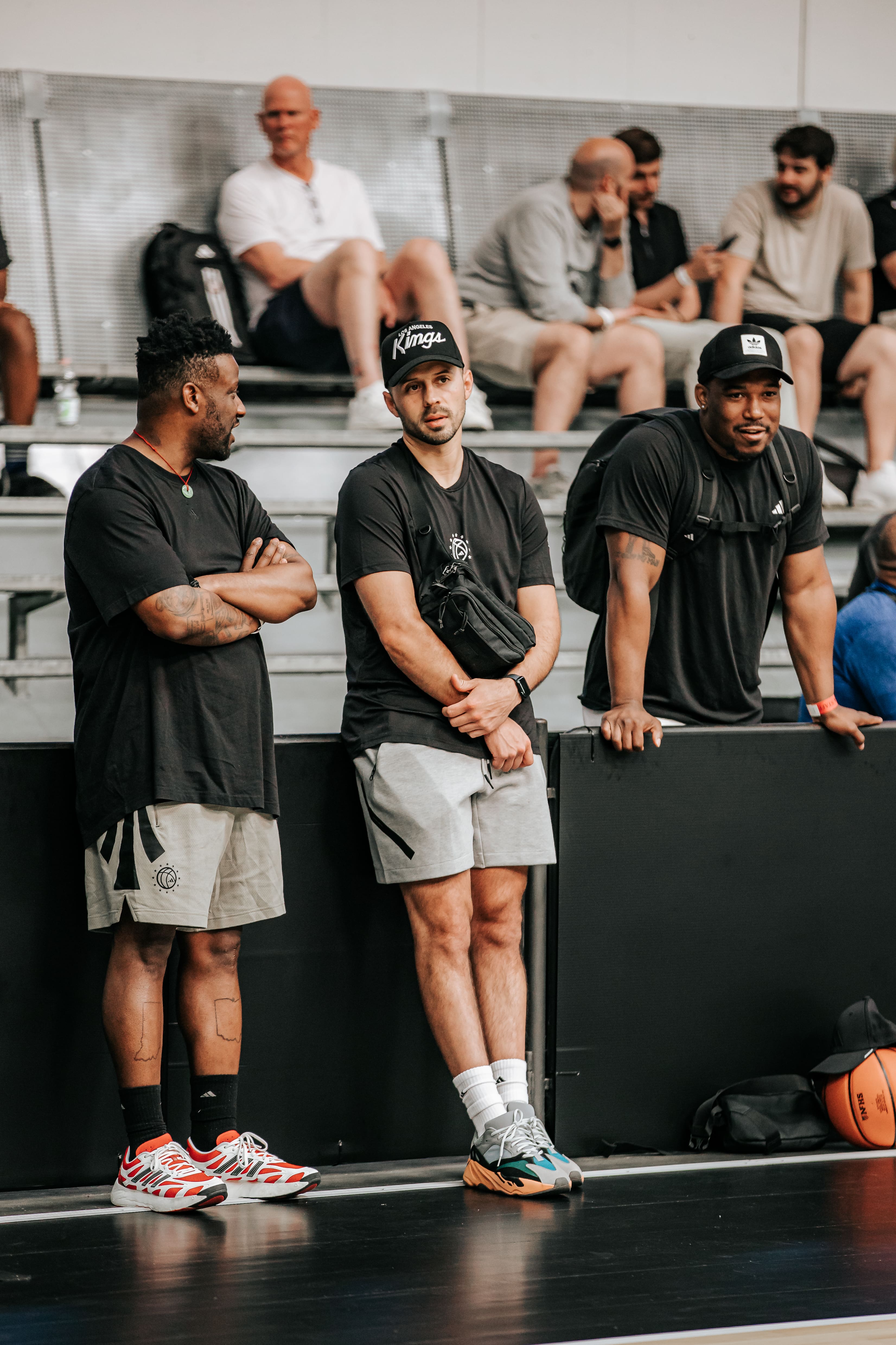Group of coaches and scouts standing courtside observing players at adidas Eurocamp 2025