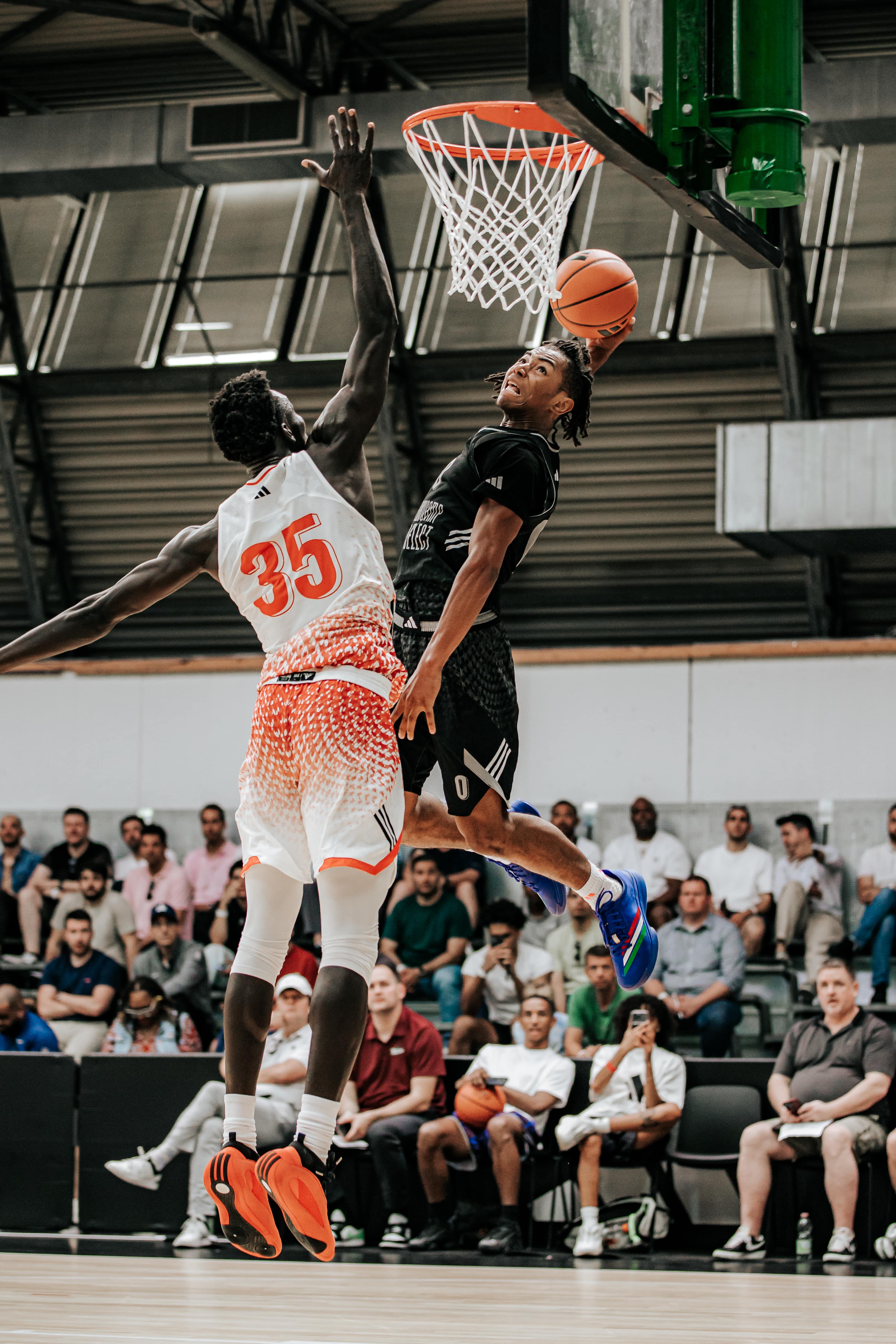Basketball player attempting a dunk over a defender during a game at adidas Eurocamp 2025