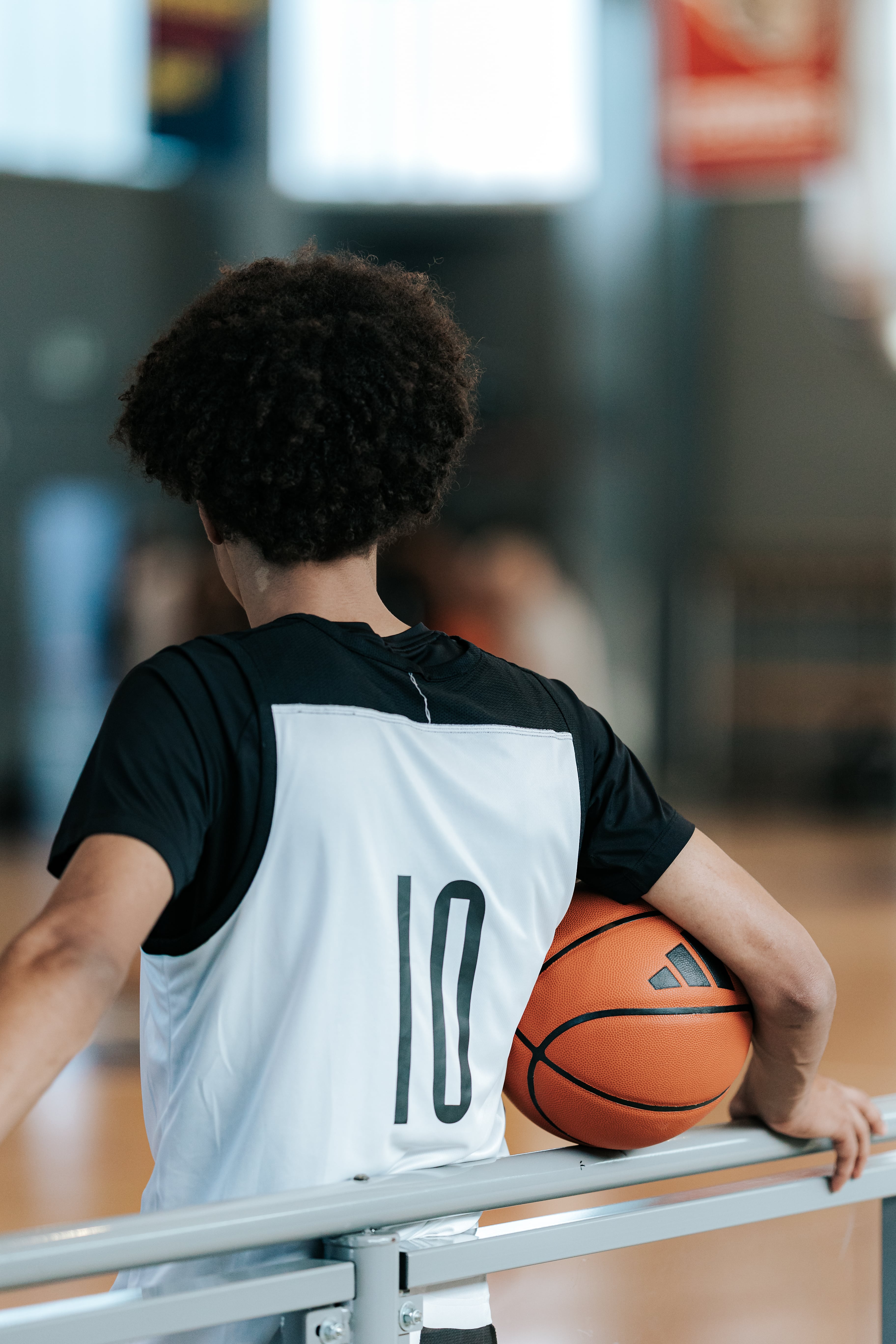 Back view of a basketball player holding a ball and watching from the sideline at adidas Eurocamp 2025